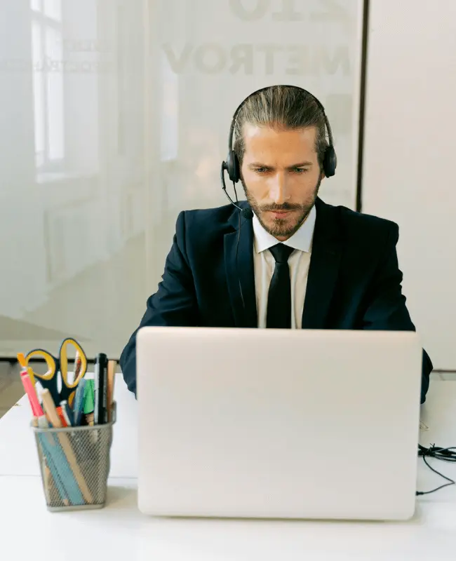 Empresario con traje haciendo rutina gratuita para aprender ingles frente a ordenador con cascos